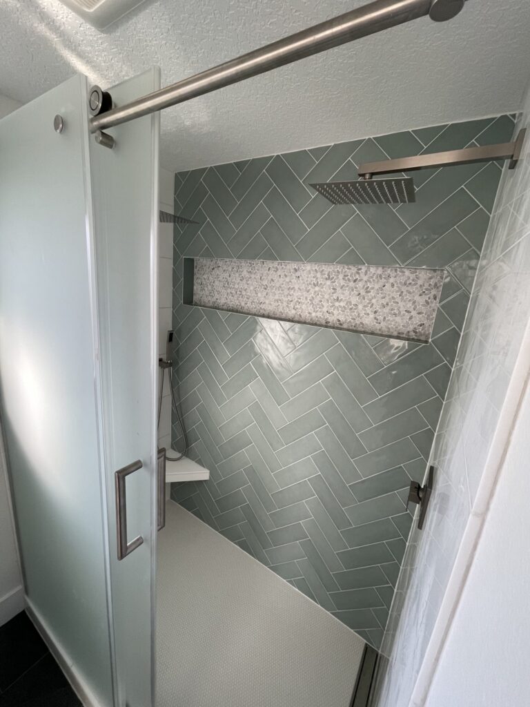 Custom shower that was part of a bathroom remodel. It involved a herringbone tile back wall with marble tile on the sides and floor. A schluter waterproofing system was used.