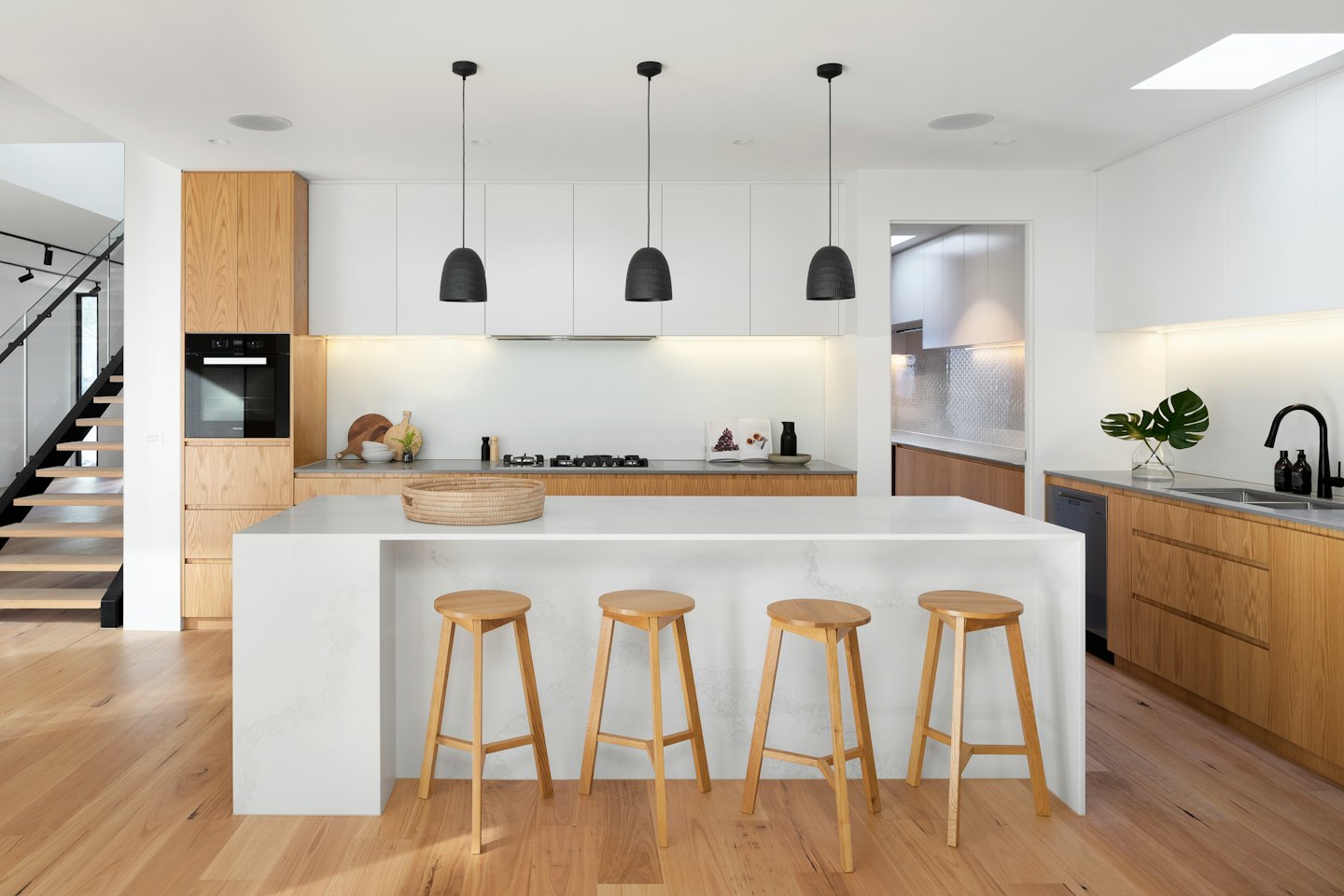 White quartz kitchen island with wooden bar stools and modern cabinetry.